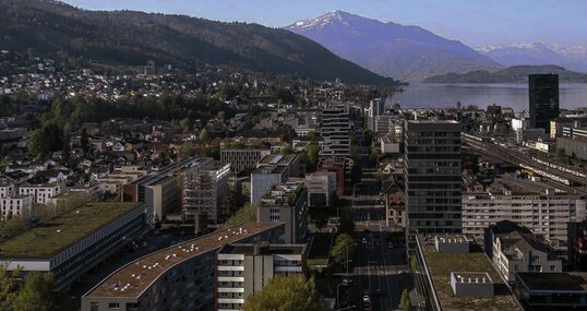 Ein Panorama der Stadt Zug mit See und Bergen im Hintergrund.